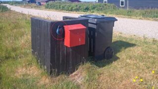 Una estructura de madera con una caja roja y un recipiente negro.