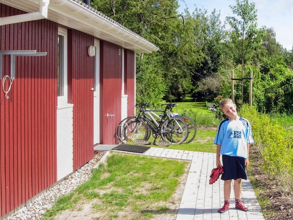 A red building with a door and windows, a pathway leading to it, and bicycles parked outside.