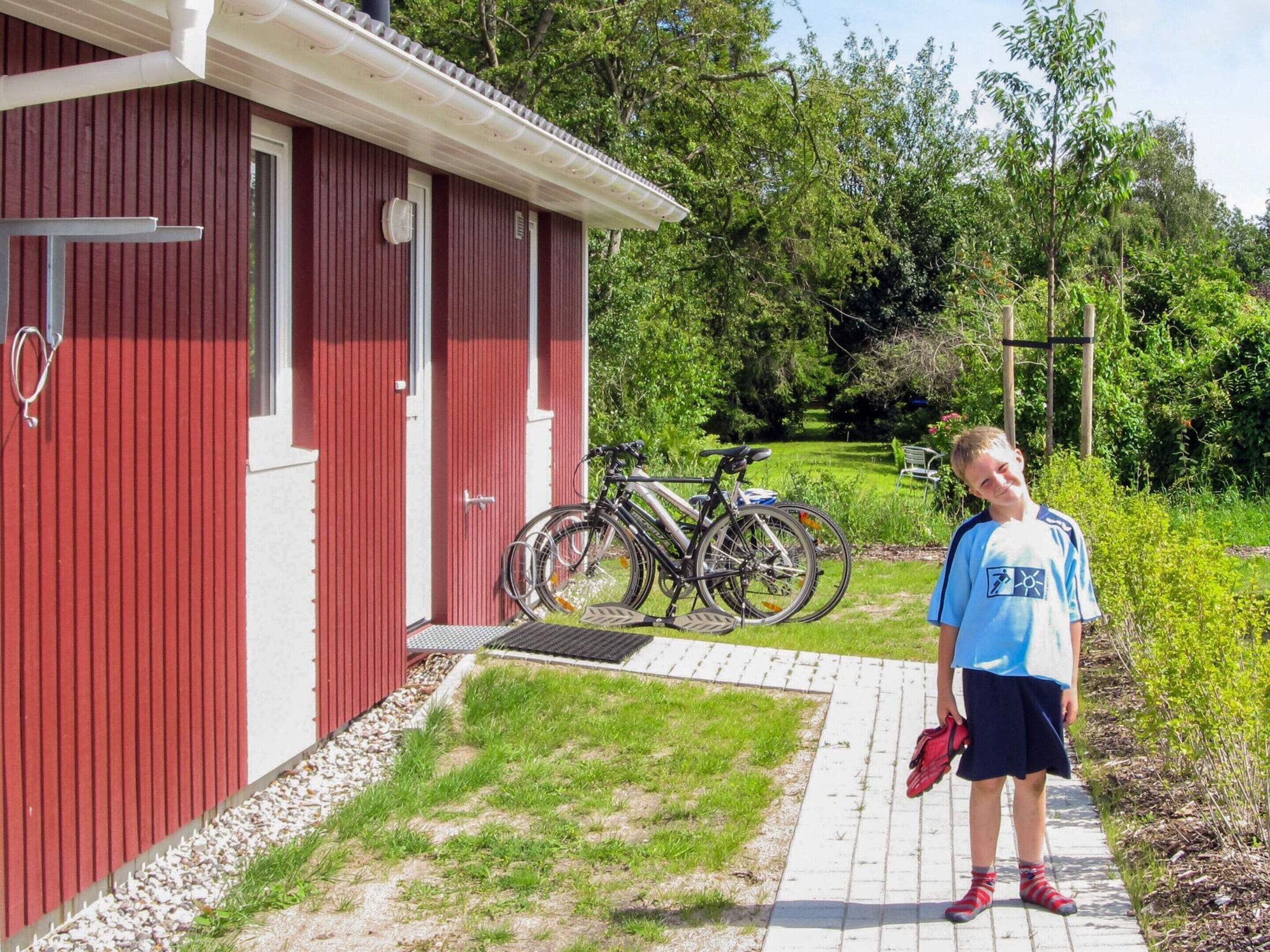 A red building with a door and windows, a pathway leading to it, and bicycles parked outside.