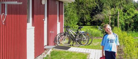 A red building with a door and windows, a pathway leading to it, and bicycles parked outside.