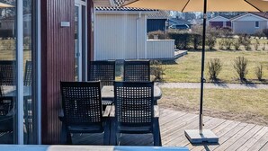 Eine Außenpatio mit Tisch und Stühlen, einem großen Sonnenschirm und Blick auf eine Wohngegend.