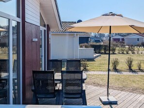 Eine Außenpatio mit Tisch und Stühlen, einem großen Sonnenschirm und Blick auf eine Wohngegend.
