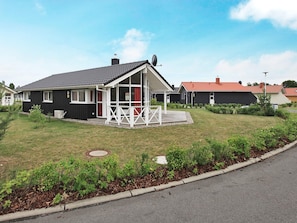 A residential property with a fenced yard, a covered porch, and a satellite dish.
