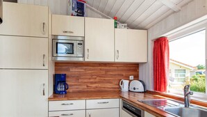 A compact kitchen with a microwave, coffee maker, toaster, and a dishwasher. - Holiday Home in GrÃ¶mmitz (Groemitz)