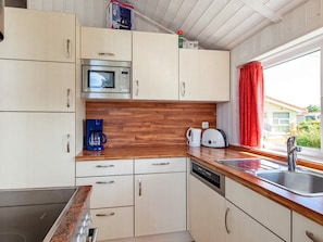 A compact kitchen with a microwave, coffee maker, toaster, and a dishwasher. - Holiday Home in GrÃ¶mmitz (Groemitz)