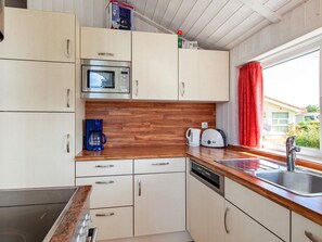 A compact kitchen with a microwave, coffee maker, toaster, and a sink. - Holiday Home in GrÃ¶mmitz (Groemitz)
