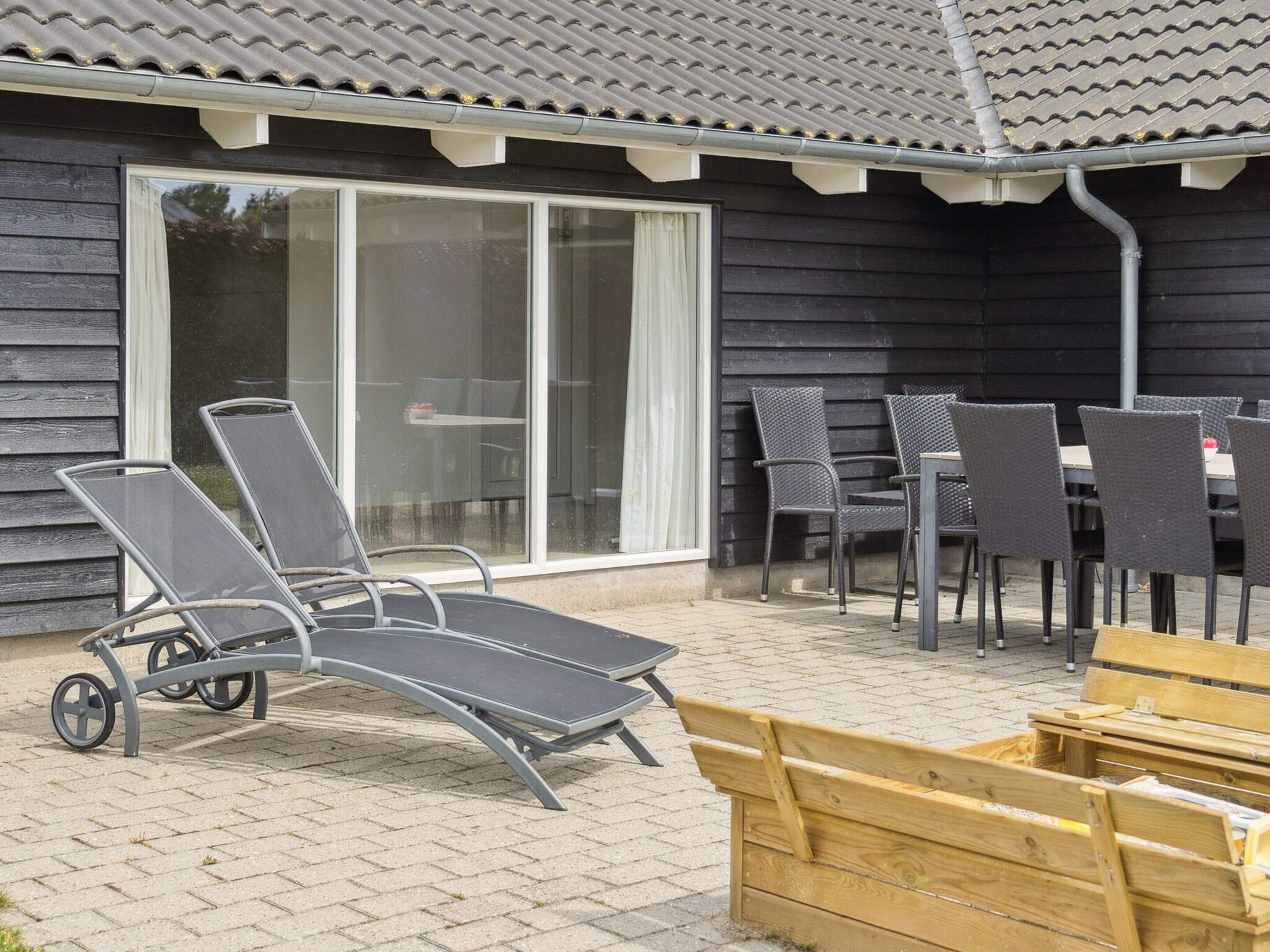Un espace patio aménagé avec une table et des chaises, un banc en bois et une porte-fenêtre coulissante donnant sur un espace intérieur.