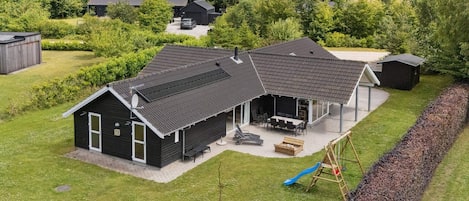 Une maison à deux étages avec une terrasse couverte et un portique avec des balançoires.