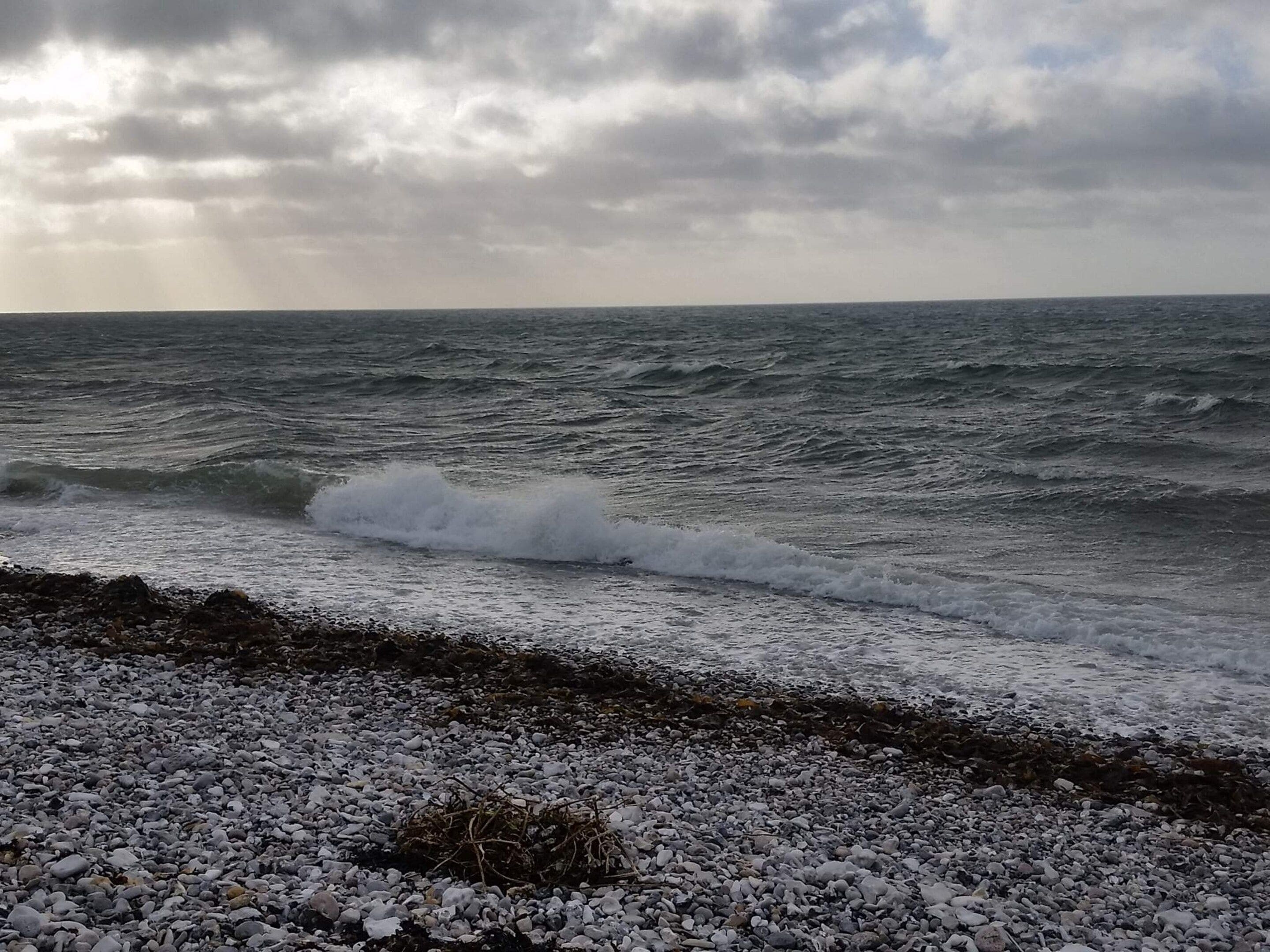 Una costa rocosa con olas rompiendo sobre las piedras.