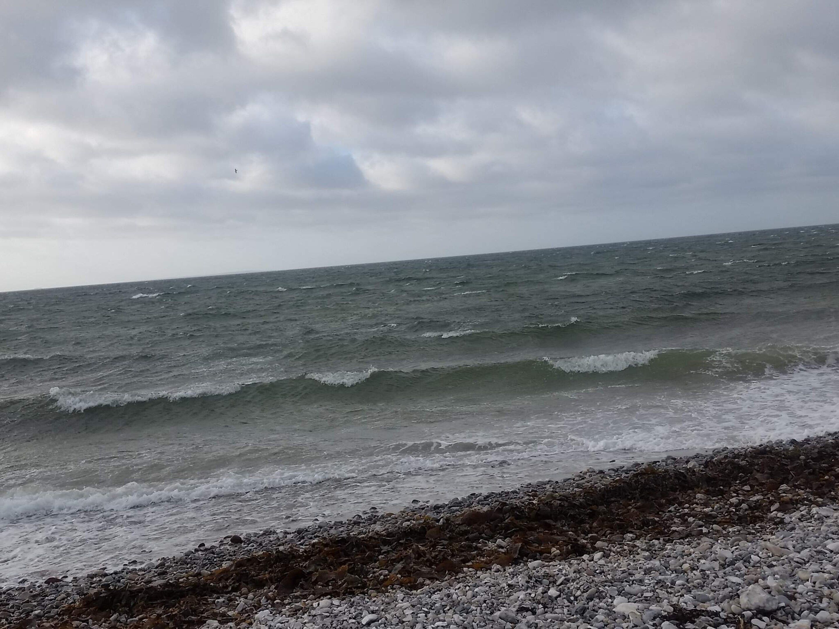 Una costa rocciosa con onde che si infrangono sulla spiaggia.