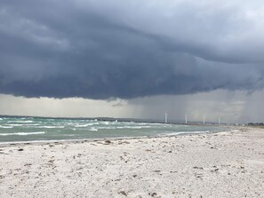 A beach with wind turbines in the distance under a stormy sky. - 5 Star Holiday Home in Ebeltoft (Ebeltoft)