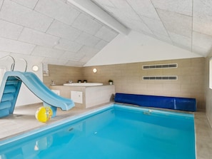 An indoor swimming pool with a blue slide, a yellow ball, and a jacuzzi. - 5 Star Holiday Home in Ebeltoft (Ebeltoft)
