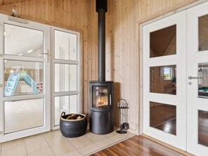 A room with a wood-burning stove, a glass door with a blue ladder, and a white door with glass panels. - 5 Star Holiday Home in Ebeltoft (Ebeltoft)