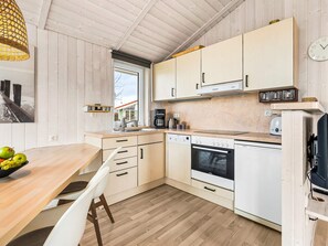Eine moderne Küche mit Holzausstattung, einem Esstisch mit Stühlen und einem Fenster mit Blick auf ein Haus.