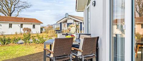 Una terraza con dos sillas de mimbre y una mesa, con vista a una zona residencial con casas y un jardín.