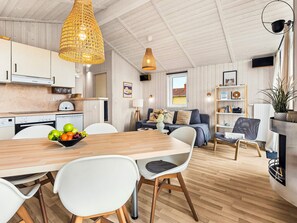 Eine moderne Küche mit weißen Schränken, einem Holztisch und einer Obstschale.