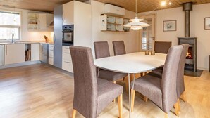 Une cuisine moderne avec des armoires blanches, un four encastré et un coin repas comprenant une table ronde et six chaises.