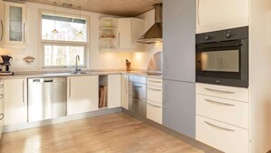 Une cuisine moderne avec des meubles blancs, un four encastré et une fenêtre qui laisse entrer la lumière naturelle.