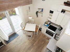 Una cocina compacta con comedor, muebles blancos y un ventanal pequeño.