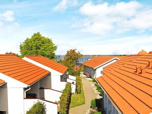 A row of white buildings with orange roofs, a clear sky, and a tree in the background. - Cozy Holiday Home in Ã†rÃ¸skÃ¸bing near Sea (Aeroskobing)