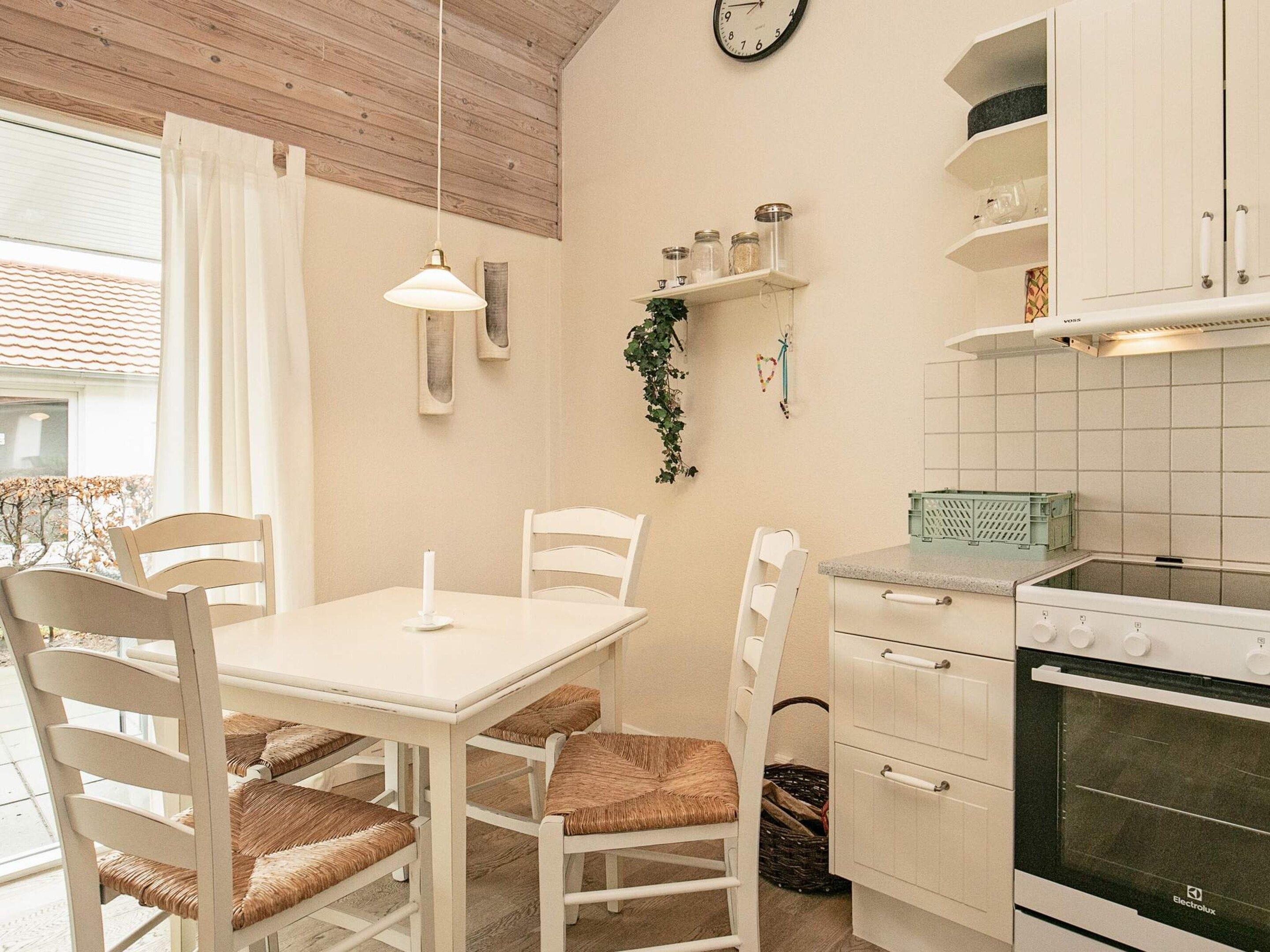 A kitchen with white cabinets, a stove, and a dining table with chairs.