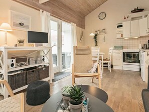 Eine moderne Küche mit weißen Schränken, einem eingebauten Backofen und einem Essbereich mit rundem Tisch und Stühlen.