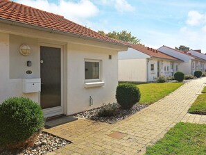 A row of single-story buildings with a tiled roof, a paved walkway, and small landscaped areas. - Cozy Holiday Home in Ã†rÃ¸skÃ¸bing near Sea (Aeroskobing)