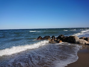 Una playa con olas, rocas y cielo despejado.