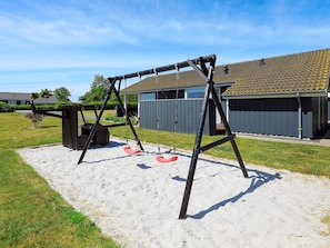 A playground with a swing set and a sandbox in a residential area. - 4 Star Holiday Home in Otterup (Otterup)