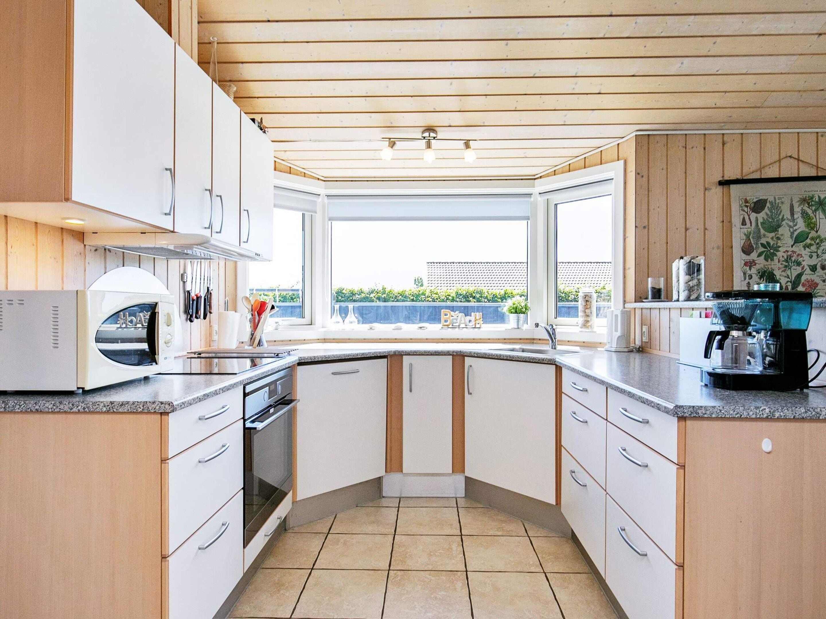 A modern kitchen with white cabinets, a built-in oven, and a coffee machine.
