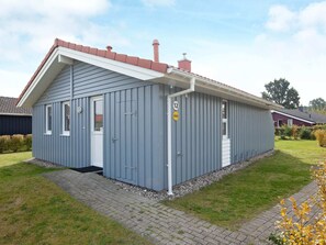 Un bâtiment d’un seul étage, avec un toit rouge, une porte blanche et une petite fenêtre.