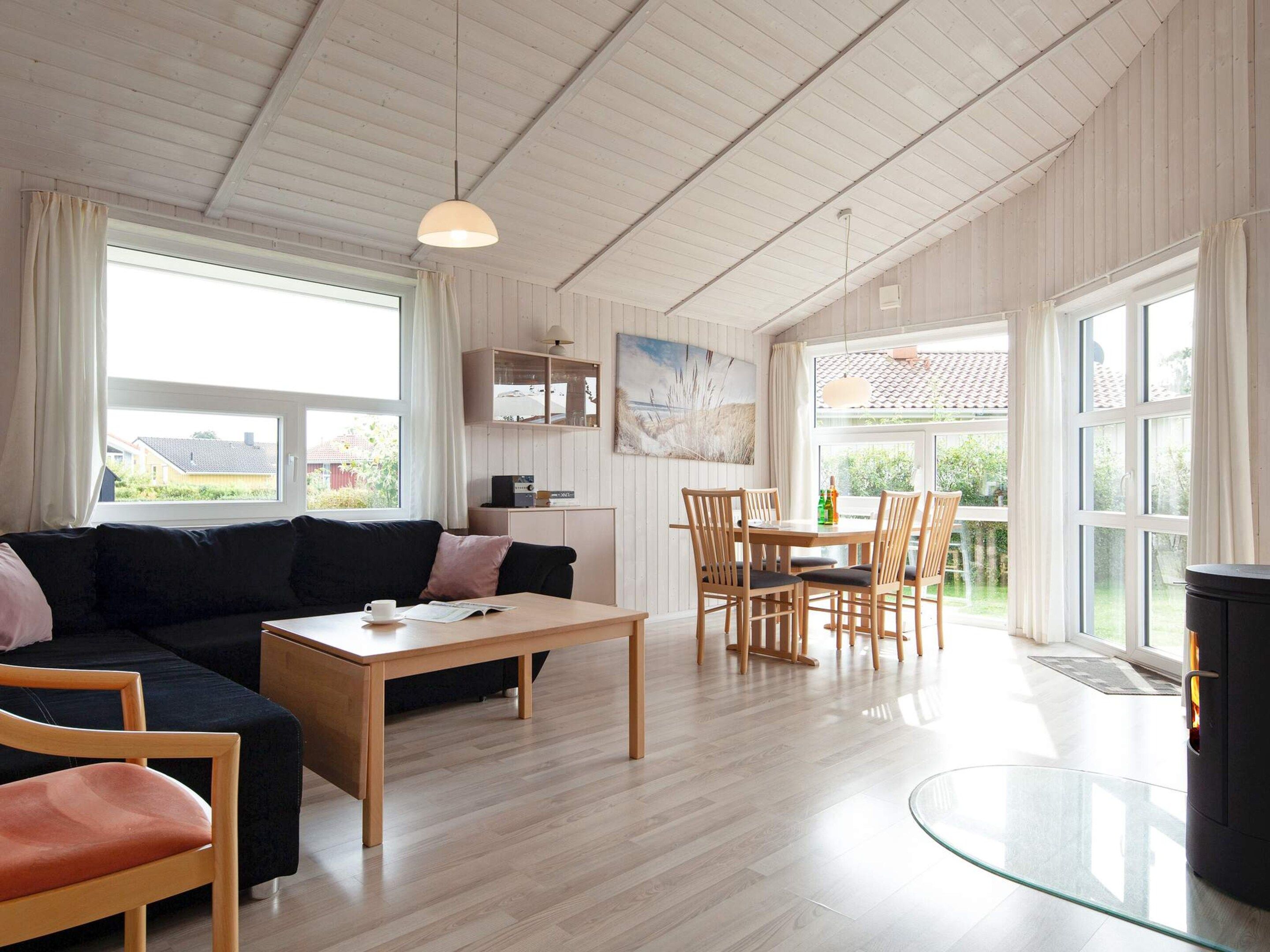 A modern living room with a sofa, a coffee table, and a dining area with chairs and a table.