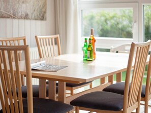 A dining table with four chairs, a bottle of orange juice, and a menu. - Holiday Home in Grömmitz (Groemitz)
