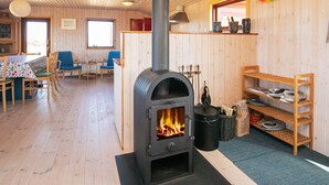 Un chalet confortable avec un poêle à bois, des murs en bois, un coin repas et une fenêtre.