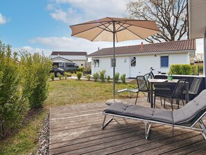 A deck with a lounge chair, a table, and an umbrella.
