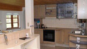 A modern kitchen with wooden cabinets, a built-in oven, and a glass-fronted spice rack. - 5 Person Holiday Home in Ans By-by Traum (Ans)