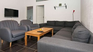 Uma sala de estar moderna com um sofá seccional, uma mesa de centro e uma TV de tela plana.