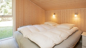A bedroom with a large bed, two wall-mounted lights, and a window with a view of greenery. - 8 Person Holiday Home in Lokken (Lokken)