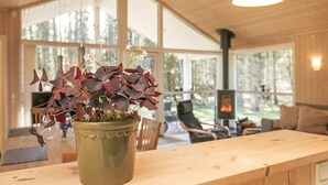 A wooden interior with a large window, a fireplace, and a potted plant on a wooden table. - 8 Person Holiday Home in Lokken (Lokken)