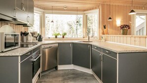 A modern kitchen with dark cabinets, stainless steel appliances, and a large window providing natural light. - 8 Person Holiday Home in Lokken (Lokken)