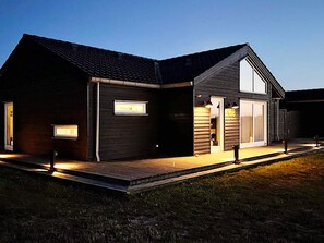 A modern two-story house with a dark exterior, large windows, and a wooden deck. - 5 Star Holiday Home in Brovst (Brovst)