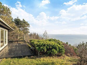 A wooden deck leading to a house with a view of the sea.