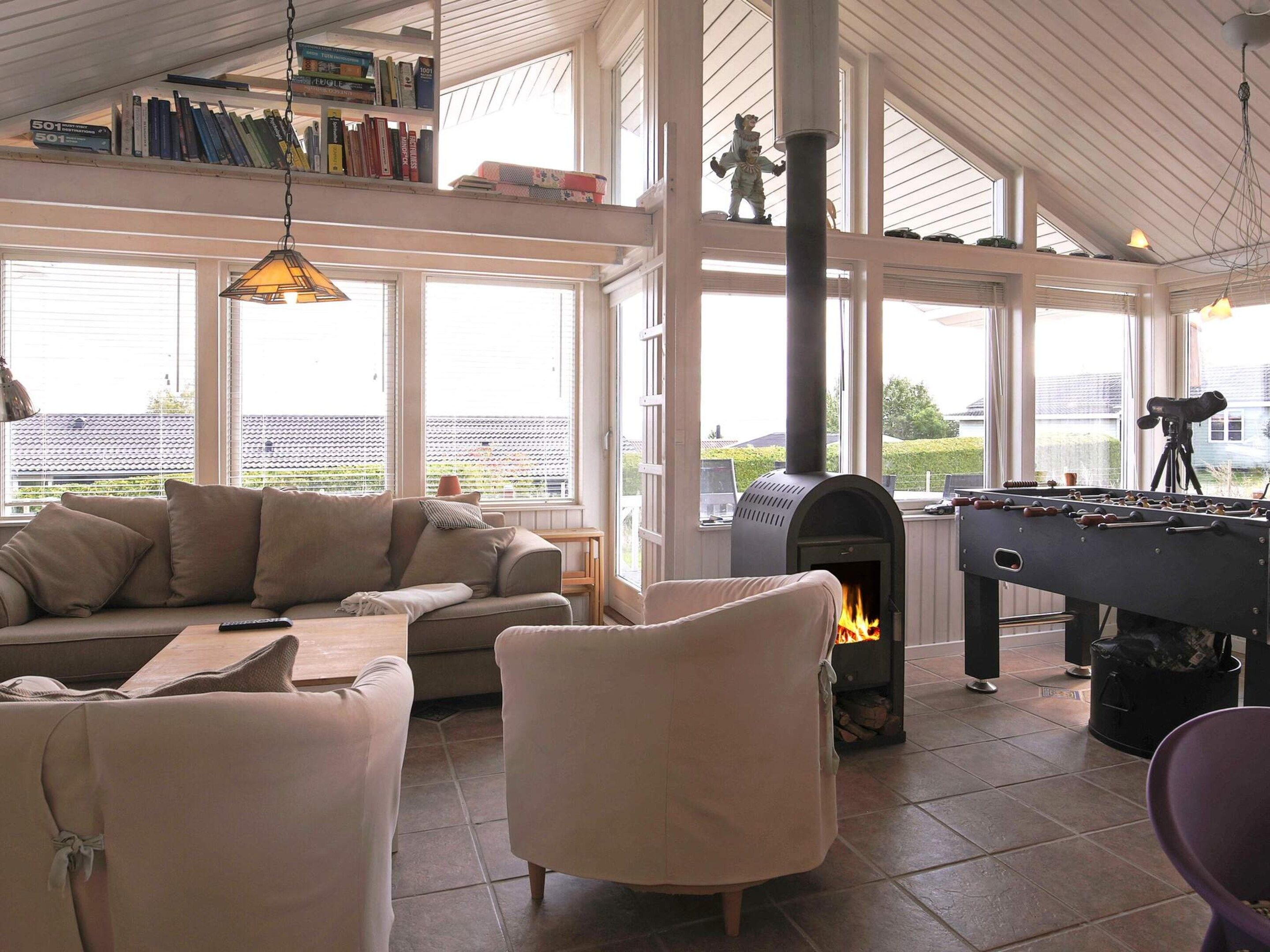 A cozy living room with a sofa, armchairs, a fireplace, and a foosball table.