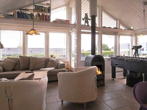 A cozy living room with a sofa, armchairs, a fireplace, and a foosball table. - 5 Star Holiday Home in Jaegerspris (Jægerspris)