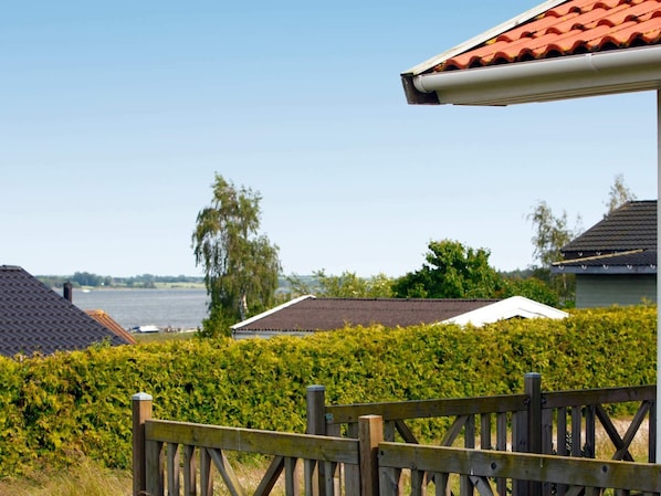 A wooden fence, a hedge, and a building with a red roof. - 5 Star Holiday Home in Jaegerspris (Jægerspris)