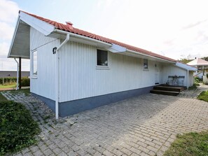 A single-story building with a red-tiled roof, a covered outdoor seating area, and a paved driveway. - 5 Star Holiday Home in Jaegerspris (Jægerspris)