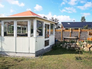 Een wit gebouw met een rood dak, een houten terras en een stenen muur.