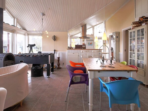 A cozy indoor space with a foosball table, a kitchen area with a bar, and a dining table with colorful chairs. - 5 Star Holiday Home in Jaegerspris (Jægerspris)