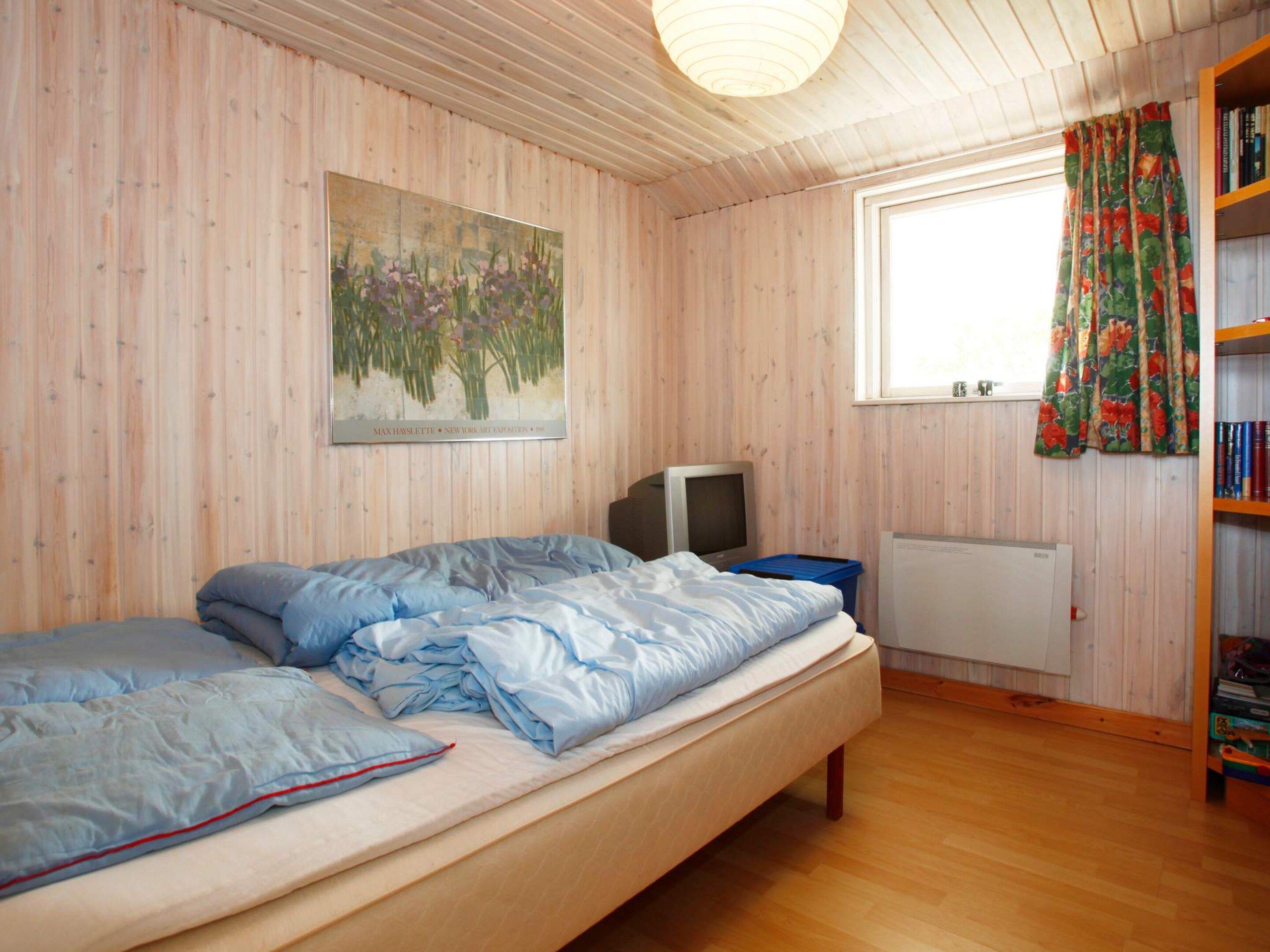 A room with a bed, a television, a radiator, and a window with curtains.