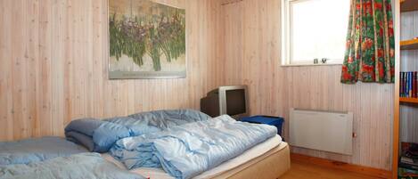 A room with a bed, a television, a radiator, and a window with curtains.